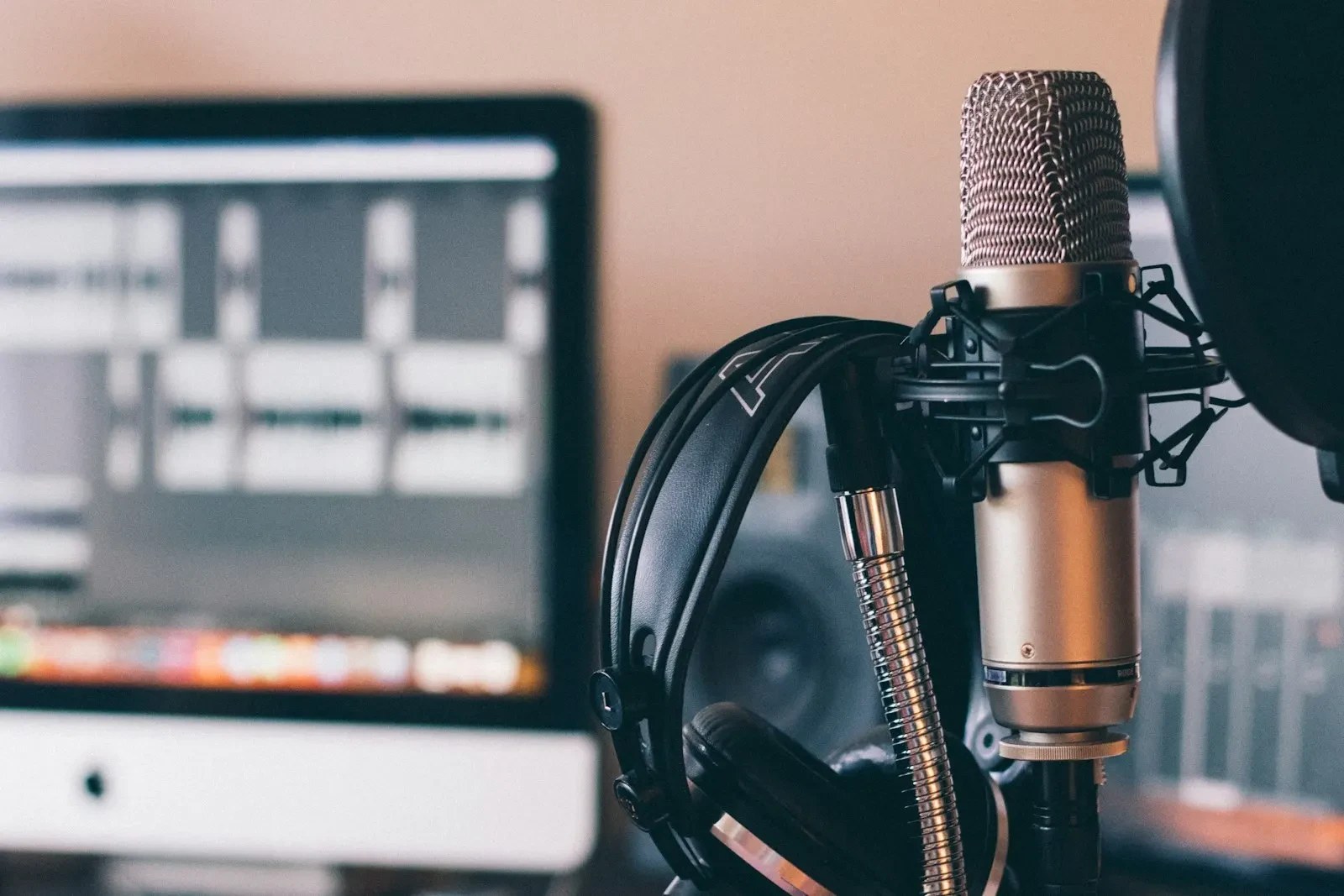 Real studio microphone and headphones beside an editing monitor, with no people present